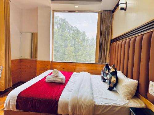a bedroom with a large bed with a window at Staynest BNB in city Centre - 3 BHK apartments - PRIVATE PARKING - BALCONY VIEW in Shimla