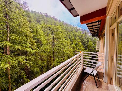 a balcony with a chair and a view of a forest at Staynest BNB in city Centre - 3 BHK apartments - PRIVATE PARKING - BALCONY VIEW in Shimla