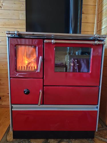 a red stove with a fire inside of it at Hidden Valley Cabin in Risan