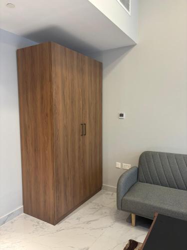 a living room with a wooden cabinet next to a couch at Dream F1 Airport Studio Pool & Gym in Abu Dhabi
