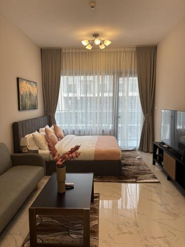 a bedroom with a bed and a couch and a tv at Dream F1 Airport Studio Pool & Gym in Abu Dhabi