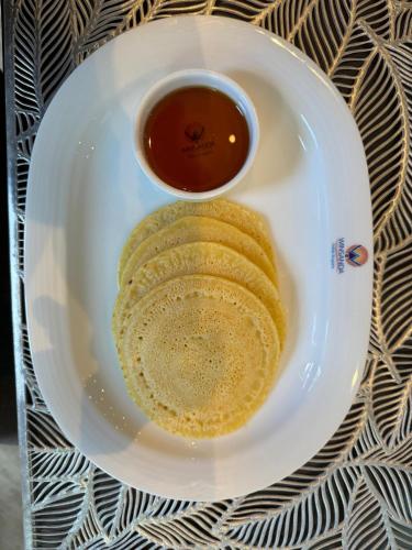 un plato de comida con una taza de salsa en Winsanda Bungalow, Nuwara Eliya, en Nuwara Eliya