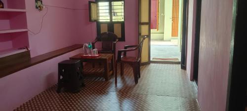 Una habitación con una mesa y dos sillas y una puerta. en Ashwin Home Stay Room, en Tiruvannāmalai