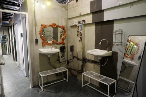 a bathroom with two sinks and a mirror on the wall at Hash Capsule Hostel Silom Soi 3 in Bangkok