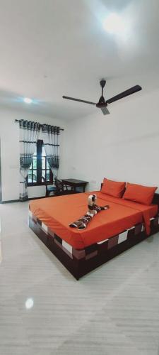 a large bed in a room with a ceiling fan at Nilaveli Beach Rooms in Nilaveli