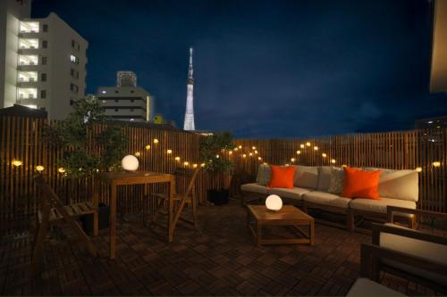 a rooftop patio with a couch and tables and lights at 凪ノ家曳舟 Naginoya Hikihune in Tokyo