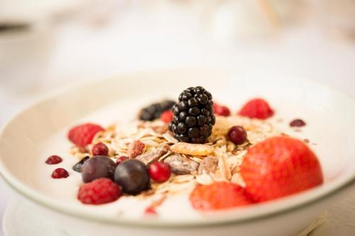 a bowl of cereal with a blackberry and berries at Boutique Hotel Kugel Wien in Vienna