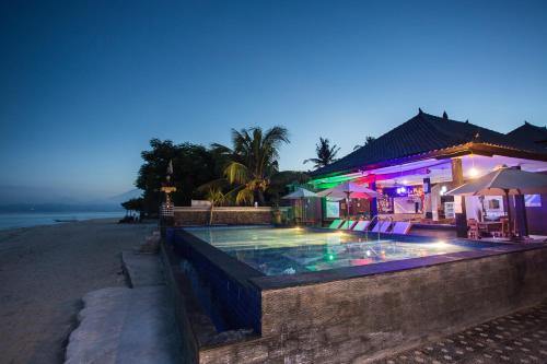 a swimming pool next to a beach at night at Linda Beach Hotel in Nusa Lembongan