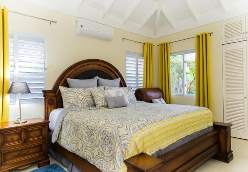 a bedroom with a large bed with yellow curtains at Tropical 3 Bedroom Villa - Ocho Rios in Priory