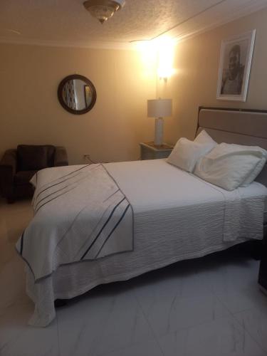 a bedroom with a large white bed and a mirror at Finest Accommodation Russell Heights Apt #A in Kingston