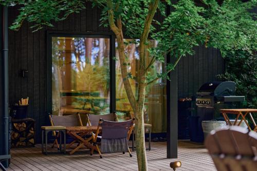a patio with chairs and a table and a tree at SAUNA FOREST CABIN 軽井沢 御代田 A棟 zen-asobi in Oiwake