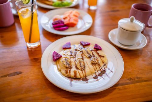 ein Tisch mit einem Teller Pfannkuchen und Obst in der Unterkunft Tegal Bamboo Cottages & Private Hot Spring in Baturaja
