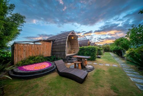 ein Hinterhof mit einer Hütte mit einer Bank und einem Tisch in der Unterkunft Tegal Bamboo Cottages & Private Hot Spring in Baturaja