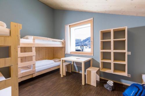 a room with bunk beds and a table and a window at Nova Casa Spinatscha Sedrun in Sedrun