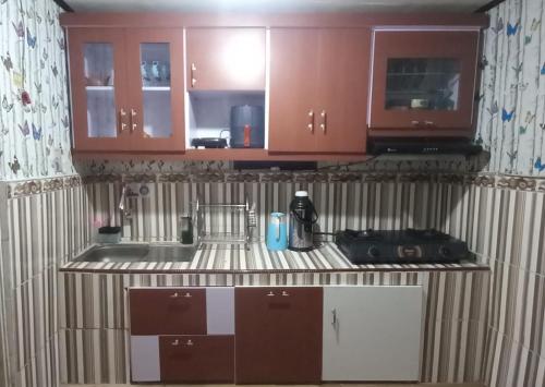 a kitchen with brown cabinets and a sink at Homestay Gaharu Syariah Dieng in Dieng