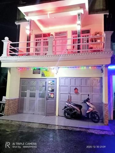 a scooter parked in front of a house at Homestay Gaharu Syariah Dieng in Dieng