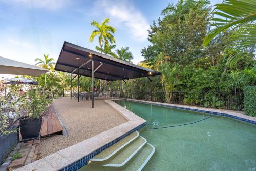 a swimming pool with chairs and a canopy over it at Vitina Studio Motel in Darwin