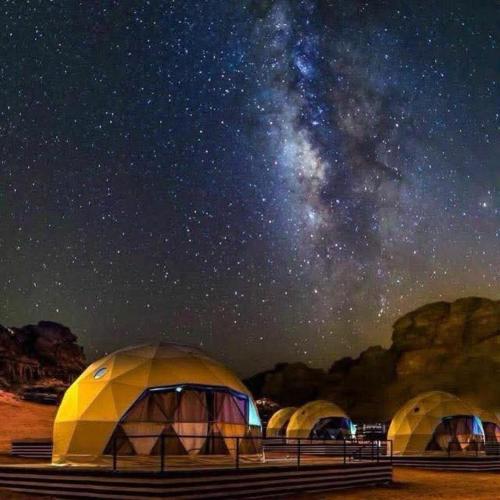 a group of tents under a starry night sky at The quiet desert in Wadi Rum