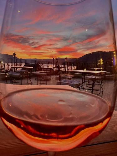 a glass of wine with a sunset in the background at Pensiunea Casa Mircea & Restaurant in Eşelniţa