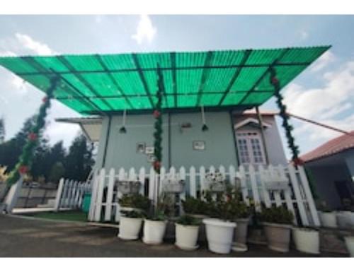 a building with a green canopy over a white fence at Le Nessa Guest House, Shillong in Shillong