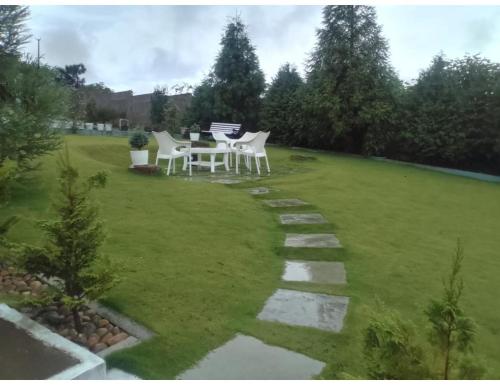 a garden with a table and chairs on a lawn at Le Nessa Guest House, Shillong in Shillong