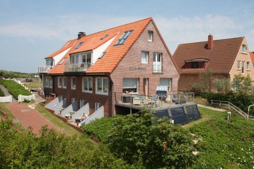une grande maison avec un toit orange dans l'établissement Haus Kap Horn, à Juist