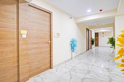 a hallway with a wooden door and marble floors at Hotel O N R in Ahmedabad