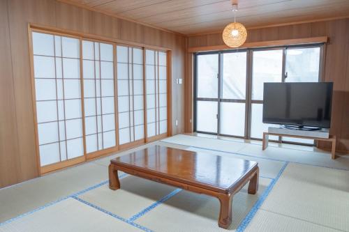 a living room with a coffee table and a flat screen tv at 12Private Stay宮古島 in Miyako Island