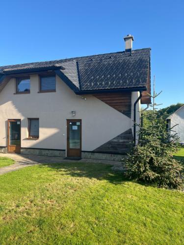 a white house with a porch and a grass yard at Apartmán Zuzka in Radoma