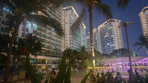a city at night with tall buildings and palm trees at Condo Azure Urban Resort Paranaque in Manila
