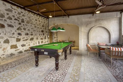 a pool table in a room with a stone wall at Maya Luxury The Quila Udaipur in Udaipur