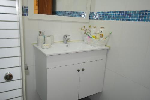 a bathroom with a white sink with toothbrushes at צימר ברחובות - Israeli Home in Rechovot