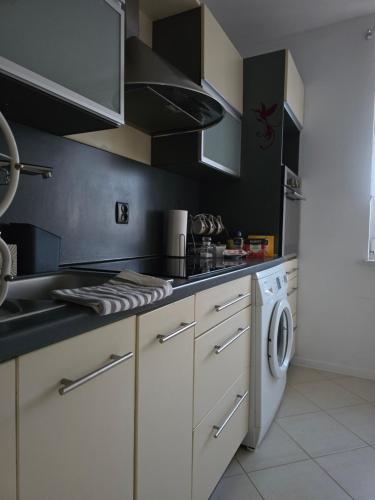 a kitchen with a sink and a washing machine at Apartament Z widokiem na Czos Mrągowo in Mrągowo