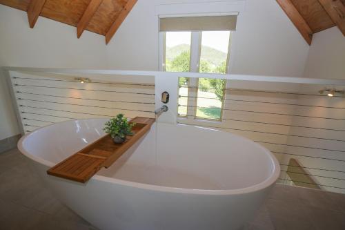 a large white bath tub in a bathroom with a window at Abby's Cottage - Cosy couples retreat in Wandiligong