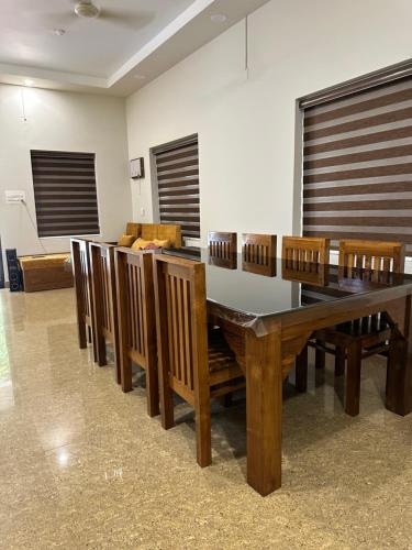 a dining room with a table and wooden chairs at Natures Adobe in Nilambūr
