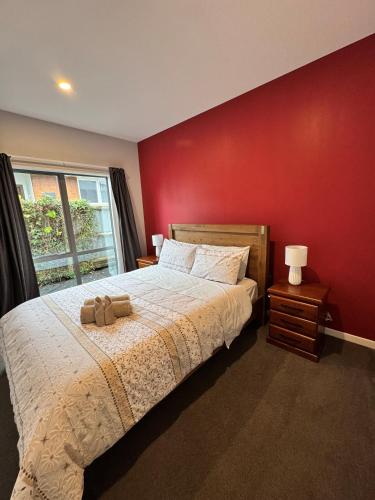 a bedroom with a large bed with a red wall at Free Parking -Kids Games Room w PS5, Arcade- Central-7 Bathrooms- Cinema in Christchurch