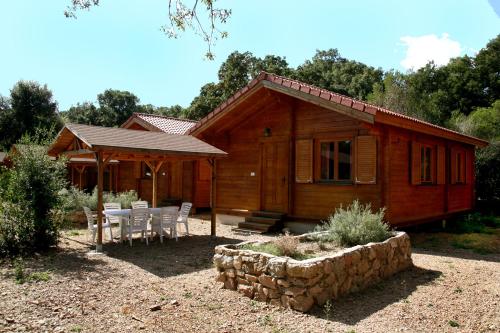 a cabin with a table and chairs in front of it at Camping U STABIACCIU in Porto-Vecchio
