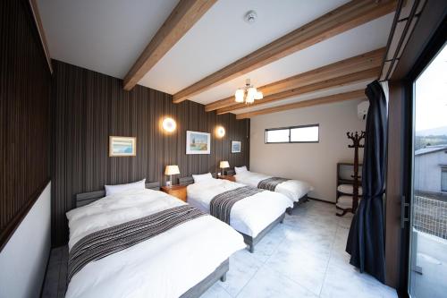 two beds in a room with wooden walls at Gran Villa Rirera Towa in Yufu