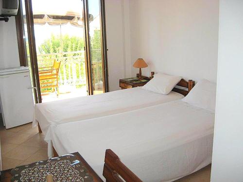 a bedroom with two white beds and a balcony at Marialena Pension in Iraion