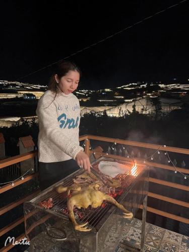 a woman is cooking food on a grill at Villa Hoa Như - View Nhà Lồng in Trai Mat