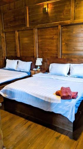 two beds in a room with wooden walls at Villa Hoa Như - View Nhà Lồng in Trai Mat