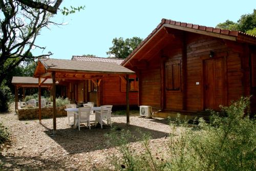 a wooden cabin with tables and chairs in front of it at Camping U STABIACCIU in Porto-Vecchio