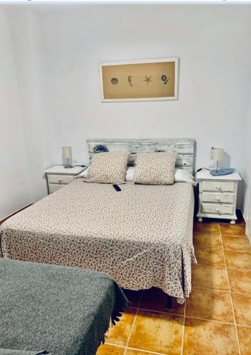 a bedroom with a bed with two night stands and two tables at Canela Garden in Isla Canela