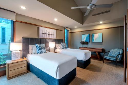 two beds in a hotel room with a desk and a bed sidx sidx sidx sidx at Yacht Club Villas on Hamilton Island by HIHA in Hamilton Island