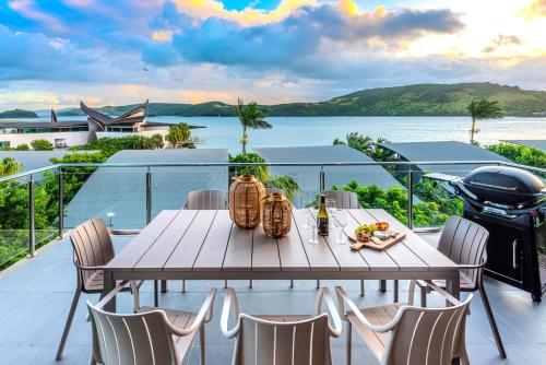 a table and chairs on a balcony with a grill at Yacht Club Villas on Hamilton Island by HIHA in Hamilton Island