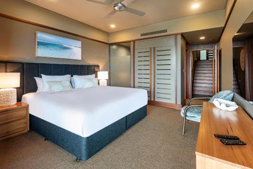a bedroom with a large bed and a desk at Yacht Club Villas on Hamilton Island by HIHA in Hamilton Island