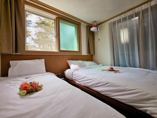 two beds in a room with flowers on them at Gamseong house next to Sung Sim Dang in Daejeon