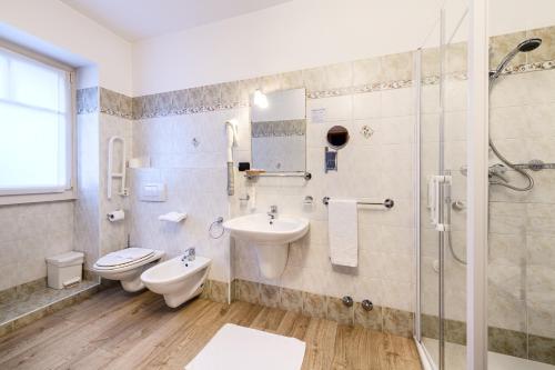 a bathroom with a toilet and a sink and a shower at Hotel Garni Le Corti in Grosotto