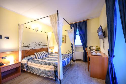 a bedroom with a canopy bed and a television at Hotel Garni Le Corti in Grosotto