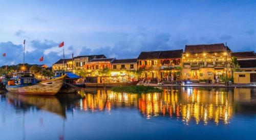 a group of buildings on a river with boats in the water at Kim's Villa Hoi An in Hoi An